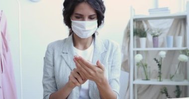 Genç iş kadını dezenfektan sprey kullanarak maske takıyor.