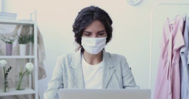 Hasta genç iş kadını, bilgisayar öksürüğü kullanarak yüz maskesi takıyor.