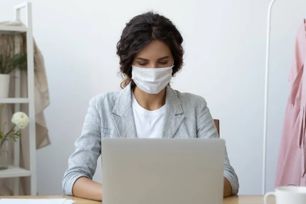 Affärskvinna i mask arbetar på bärbar dator sittande på arbetsplatsen skrivbord — Stockfoto