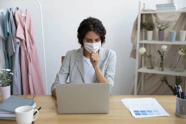 Unhealthy businesswoman in mask seated at desk and coughing — Stock Photo, Image