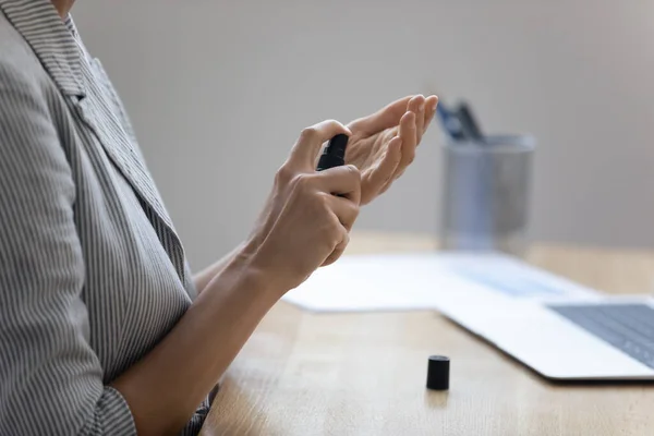 Woman cleans hands using sanitizer spray at workplace — Stock Photo, Image