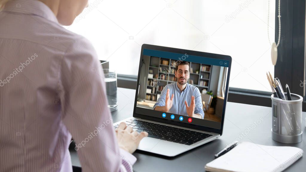 Woman negotiating via internet using laptop, view over female shoulder