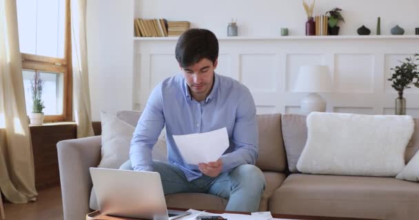 Jeune homme vérifiant les factures à payer en ligne à la maison — Video