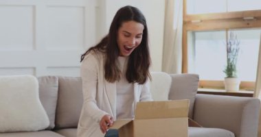 Heyecanlı genç bayan müşteri evde paket kutusu açıyor.