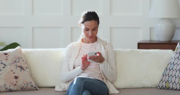 Happy millennial vrouw met behulp van mobiele telefoon in gezellig appartement — Stockvideo