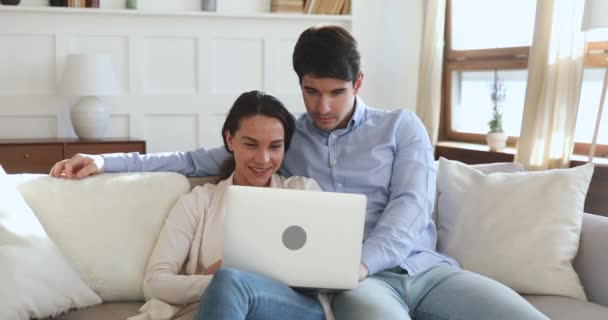 Счастливая молодая пара выигрывает онлайн на ноутбуке, празднуя победу — стоковое видео