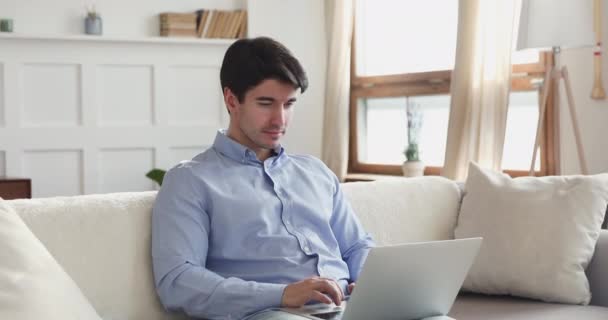 Aufgeregter junger Mann nutzt Laptop zu Hause lizenzfreies Stockvideo