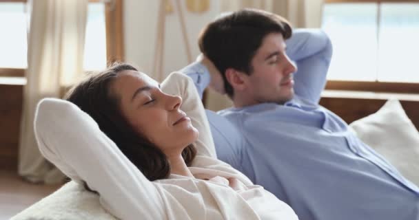 Lächelndes junges Paar entspannt mit geschlossenen Augen auf dem Sofa — Stockvideo