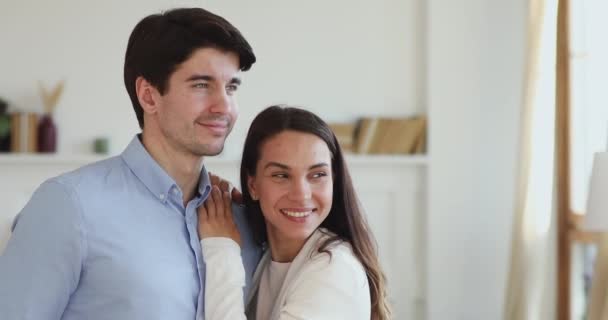 Sorrindo jovem casal de ligação olhando para longe sonhando com nova casa — Vídeo de Stock