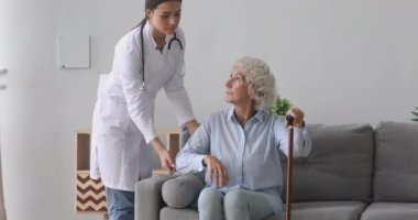 Üniformalı genç hemşire engelli, ağarmış kadına yardım ediyor..