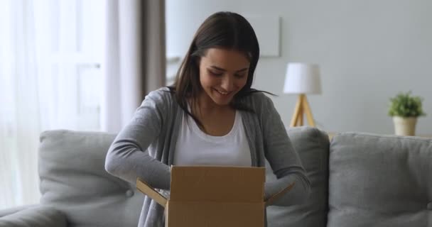 Gelukkig jong vrouwelijk cliënt uitpakken kartonnen pakket. — Stockvideo