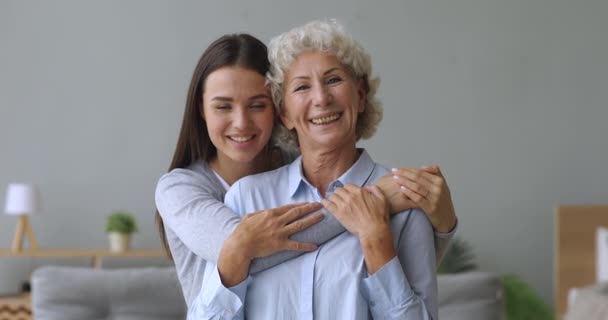 Glücklich liebevolle erwachsene Enkelin umarmt lächelnde Oma mittleren Alters. — Stockvideo