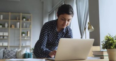 Dizüstü bilgisayarda çalışan konsantre genç Hintli kadın..