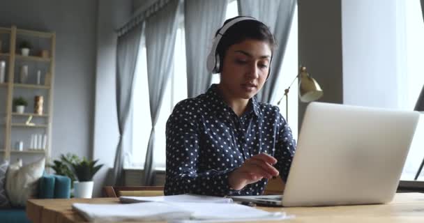 Giovane studente indiano concentrato indossando cuffie wireless, studiando online . — Video Stock