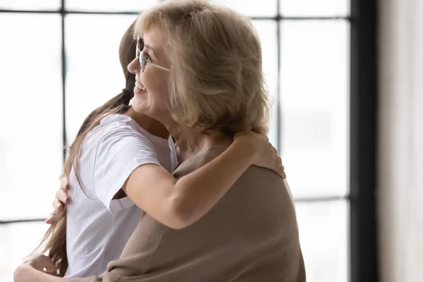 Happy elderly mother and adult daughter hugging after fight