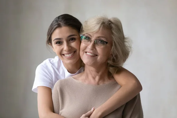 Smiling middle-aged mother and adult daughter hugging