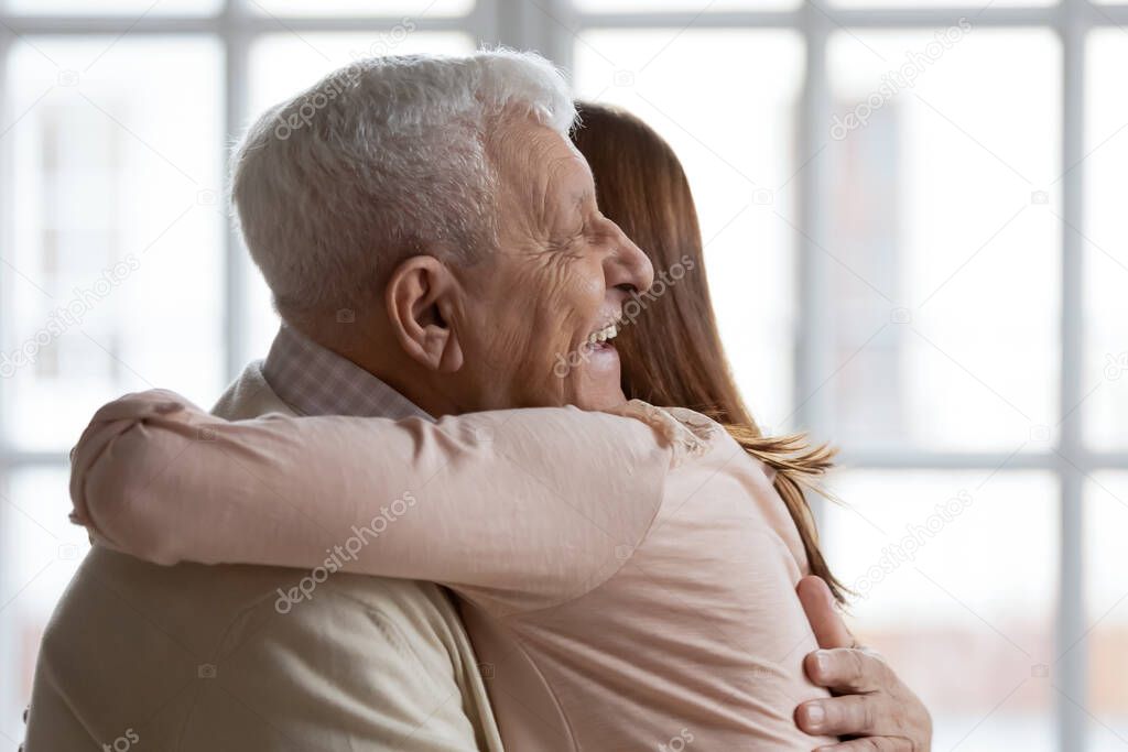 Closeup image elderly grandfather hugs adult granddaughter