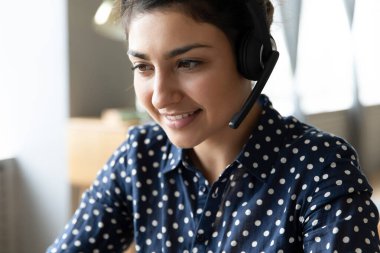 İnternette çalışan, kulaklık takan gülümseyen Hintli kadın.