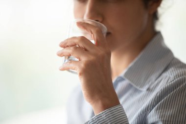 Hintli genç bir kadın saf maden suyu içiyor.