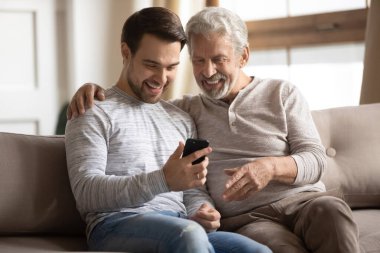 Çok mutlu bir baba ve yetişkin bir oğul, akıllı telefon kullanıyor.