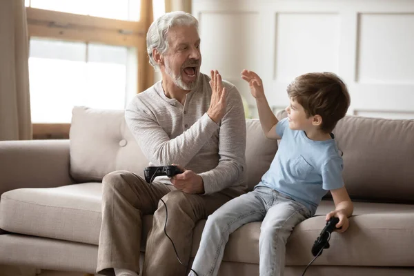 Excited little boy play video game relax with grandfather — Stock Photo, Image