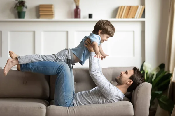 Feliz padre joven jugando en casa con su hijo pequeño —  Fotos de Stock
