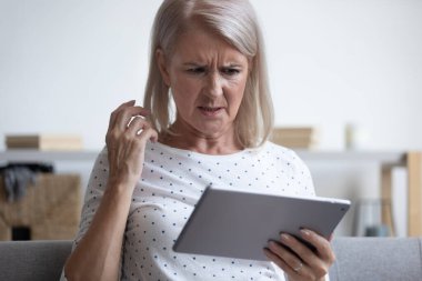 Orta yaşlı bir kadın bilgisayar tabletine bakıyor..