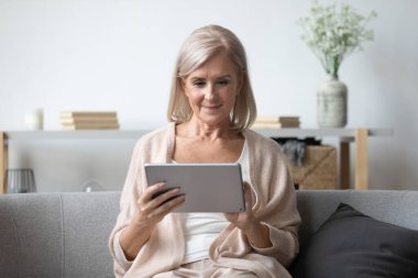 Tablet kullanan orta yaşlı hoş bir kadının portresi.