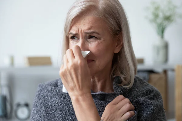 Unhealthy older woman covered in plaid, using paper tissue. — Stock Photo, Image