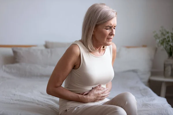 Unhealthy middle aged woman suffering from strong stomach ache. — Stock Photo, Image