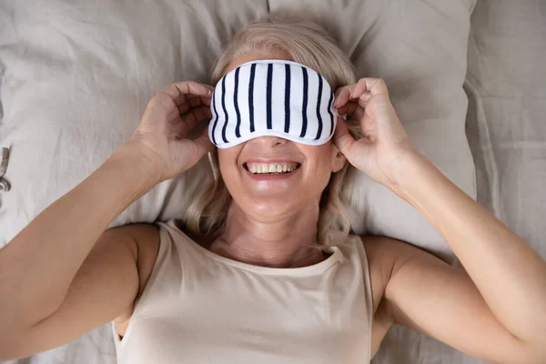 Smiling middle aged woman wearing sleeping mask. — Stock Photo, Image