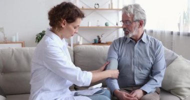 Kadın doktor, elektronik tonometre kullanarak yaşlı hastayı kontrol ediyor.