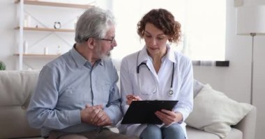 Kadın doktor reçeteyi açıklıyor. Yaşlı erkek hastayla konuşuyor.