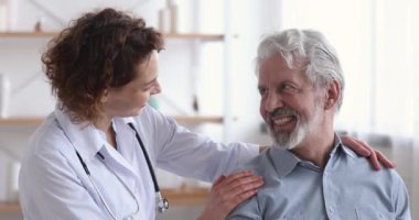 Şefkatli bayan doktor mutlu kıdemli hastayı kucaklıyor.