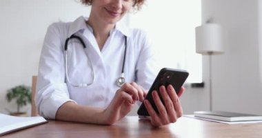 Akıllı telefon uygulamaları kullanan kadın doktor. Uzaktan kumandalı hastaya danışıyor. Yakın plan.