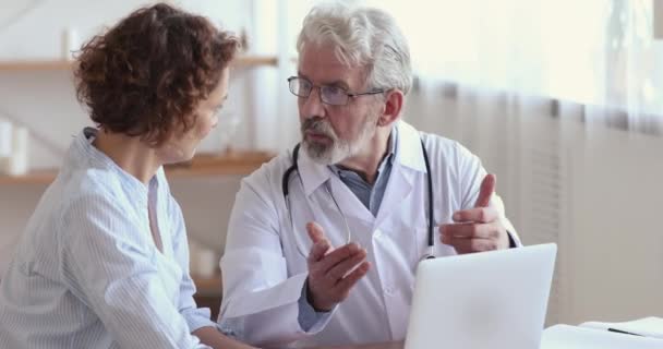 Médico velho consultando paciente do sexo feminino mostrando resultados do teste no laptop — Vídeo de Stock