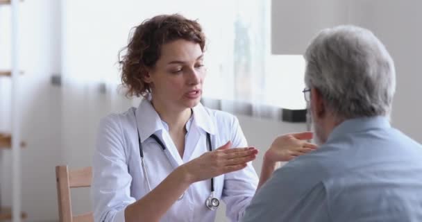 Doctora hablando examinando paciente senior en visita en hospital — Vídeos de Stock