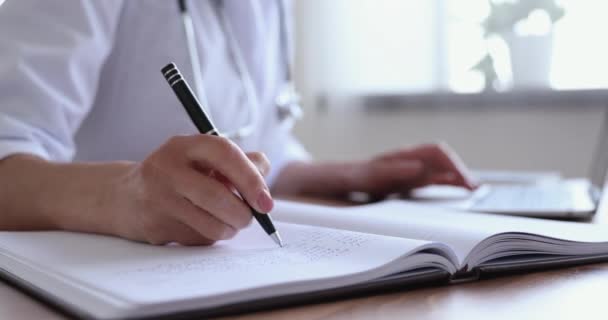 Close up of female doctor making notes doing online research — Stock Video