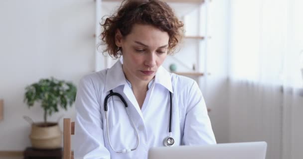 Médico femenino serio perdido en pensamientos haciendo investigación en línea — Vídeo de stock