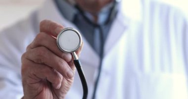 Kıdemli doktor steteskopu elinde tutuyor.