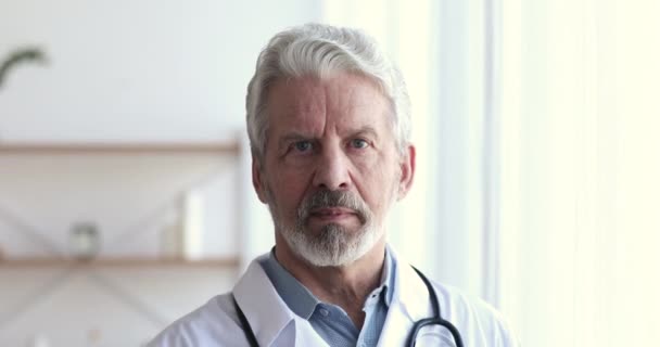Confiado médico profesional senior masculino mirando a la cámara, retrato de primer plano — Vídeo de stock