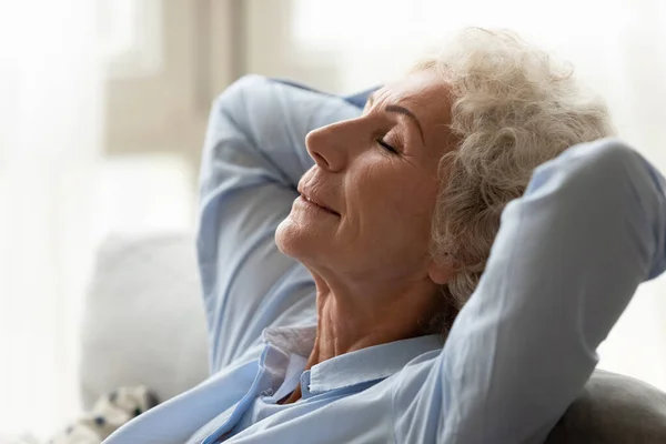 Calm old woman relax on couch in living room