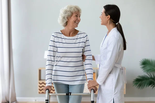Positive old lady with walker talk with caring nurse — Stock Photo, Image