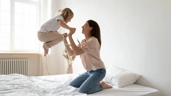 Excited little girl jump high playing with mom — Stock Photo, Image