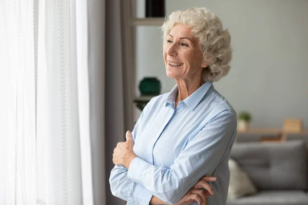 Lächelnde ältere Frau blickt in die Ferne und fühlt sich glücklich — Stockfoto