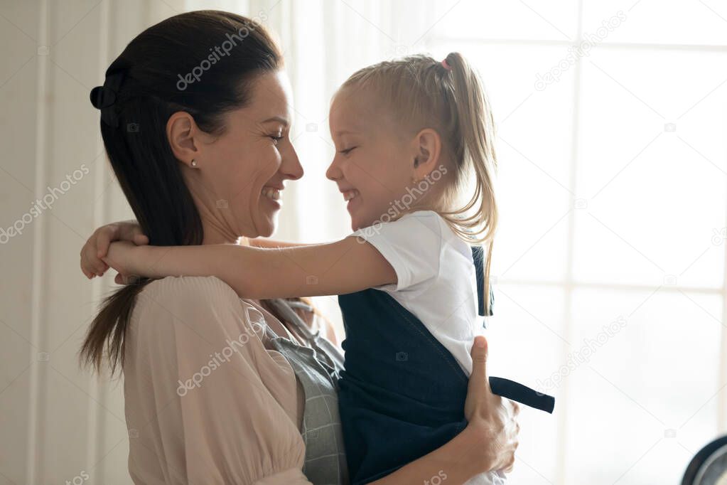 Smiling mom and little daughter hug sharing sweet moment