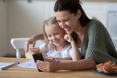 Gülümseyen anne ve kızı birlikte poz veriyorlar.