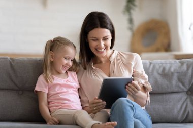 Mutlu anne ve kız tablette birlikte oynuyorlar.