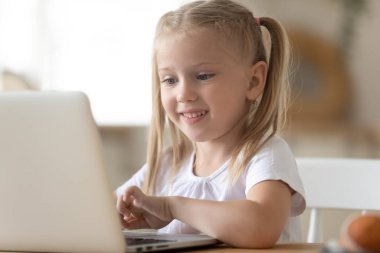 Akıllı küçük kız evde bilgisayarla öğrenim görüyor.