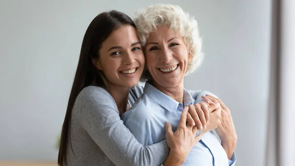 Porträtt av leende mogen mamma och vuxen dotter kramas — Stockfoto